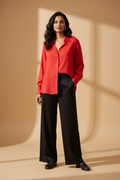 Model wearing a red relaxed collared shirt with black wide-leg trousers