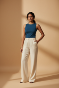 Model wearing a teal sleeveless fitted top with cream wide-leg pants